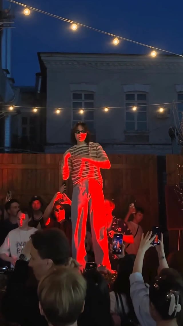 A dancer in a striped shirt moves under red stage lighting.